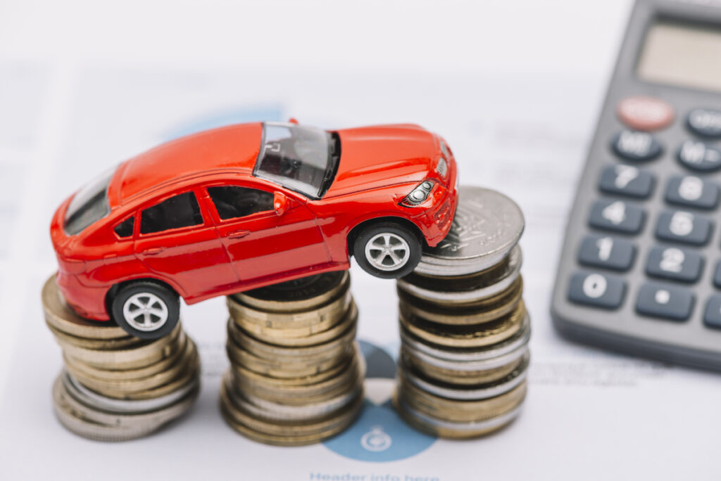 Toy car atop coins symbolizing car insurance