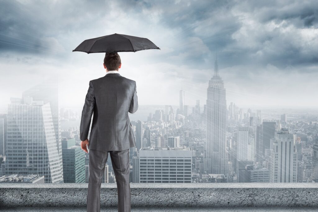 A businessman under an umbrella overlooking the city
