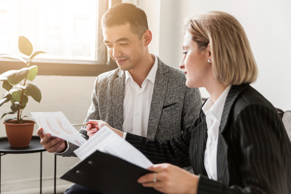 Dos profesionales de negocios revisan juntos diferentes tipos de pólizas de seguro comercial.