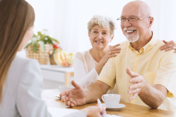Una pareja de ancianos consulta con un corredor sobre una póliza de seguros.